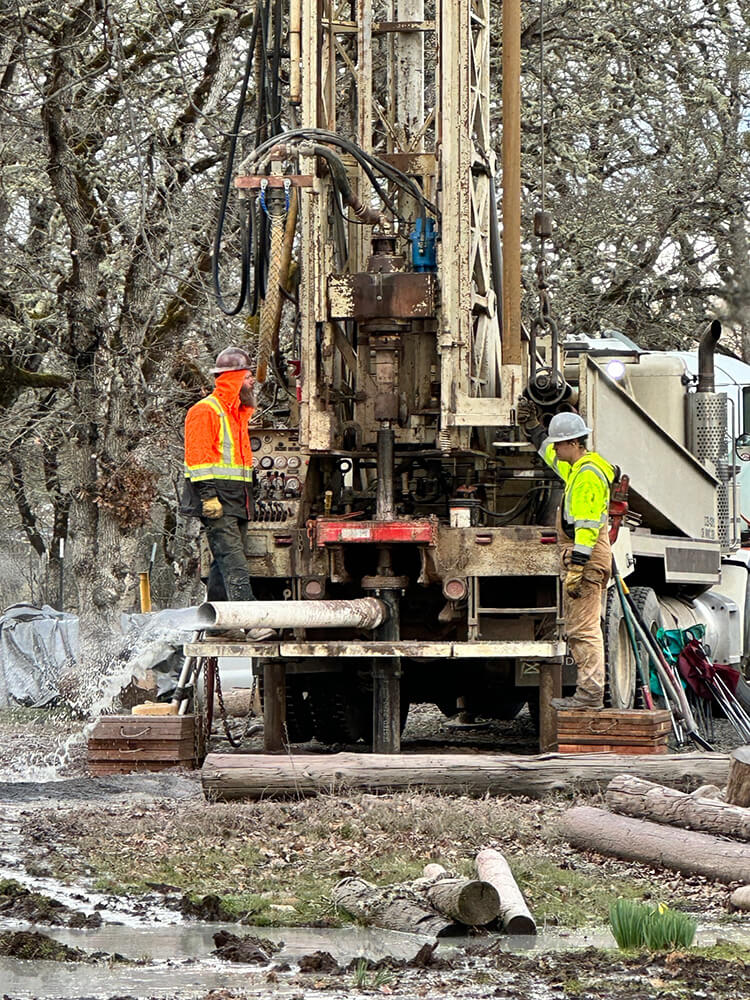 A photo showing 2 men working with well drilling equipment in Southern Oregon
